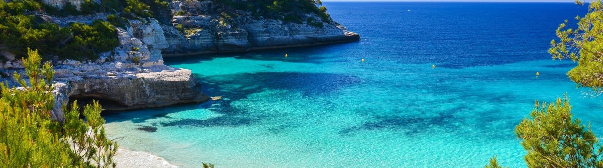 Secluded beach with turquoise sea water Cala Mitjaneta Menorca island Spain shutterstock_189270002 1200x335